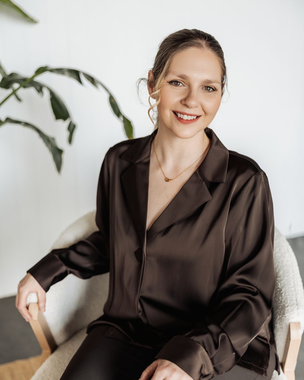 Tilly seated in an armchair in a bright room, smiling towards the camera.